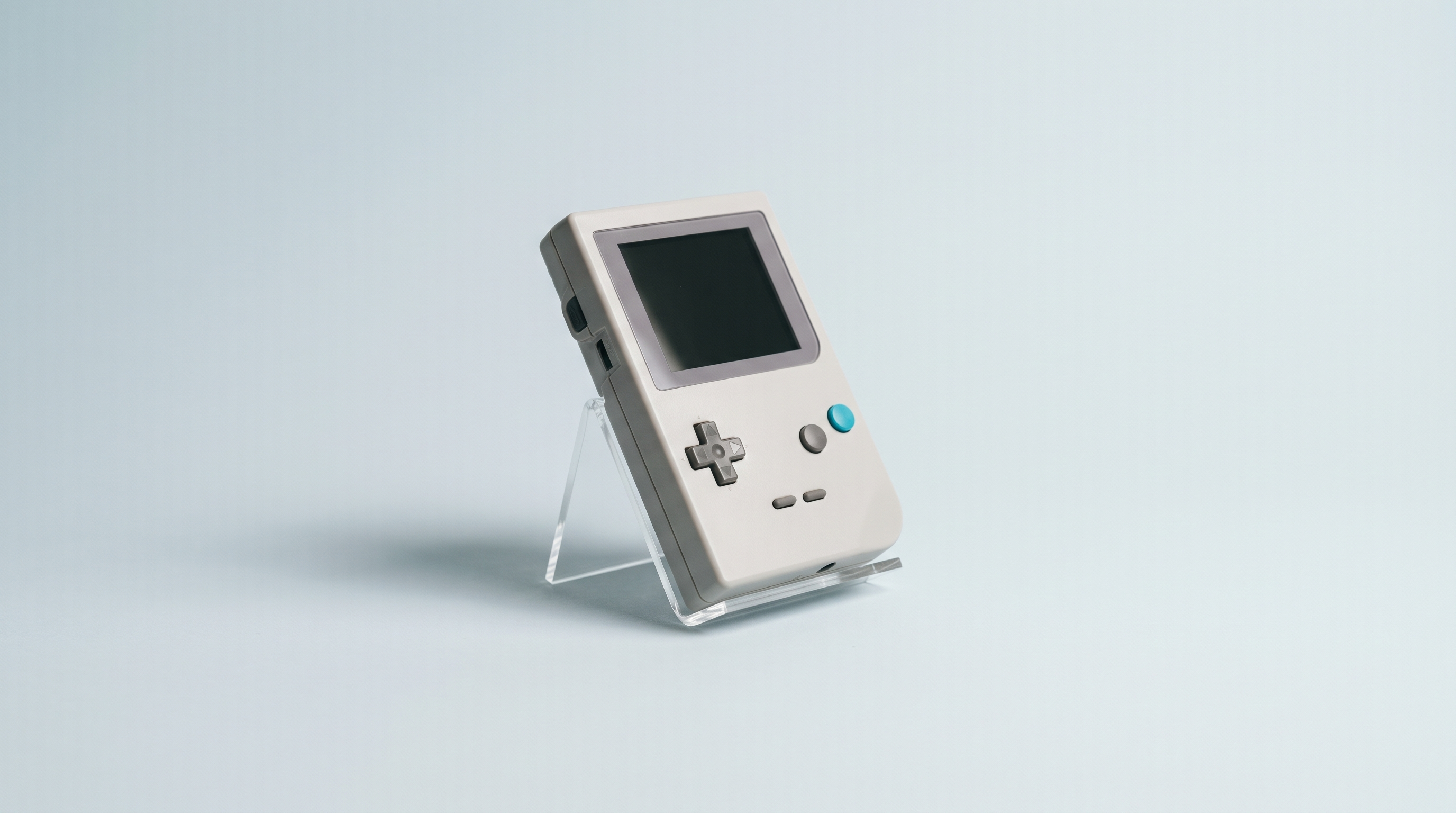 Console portable rétro inclinée sur un support transparent, boutons nets au premier plan