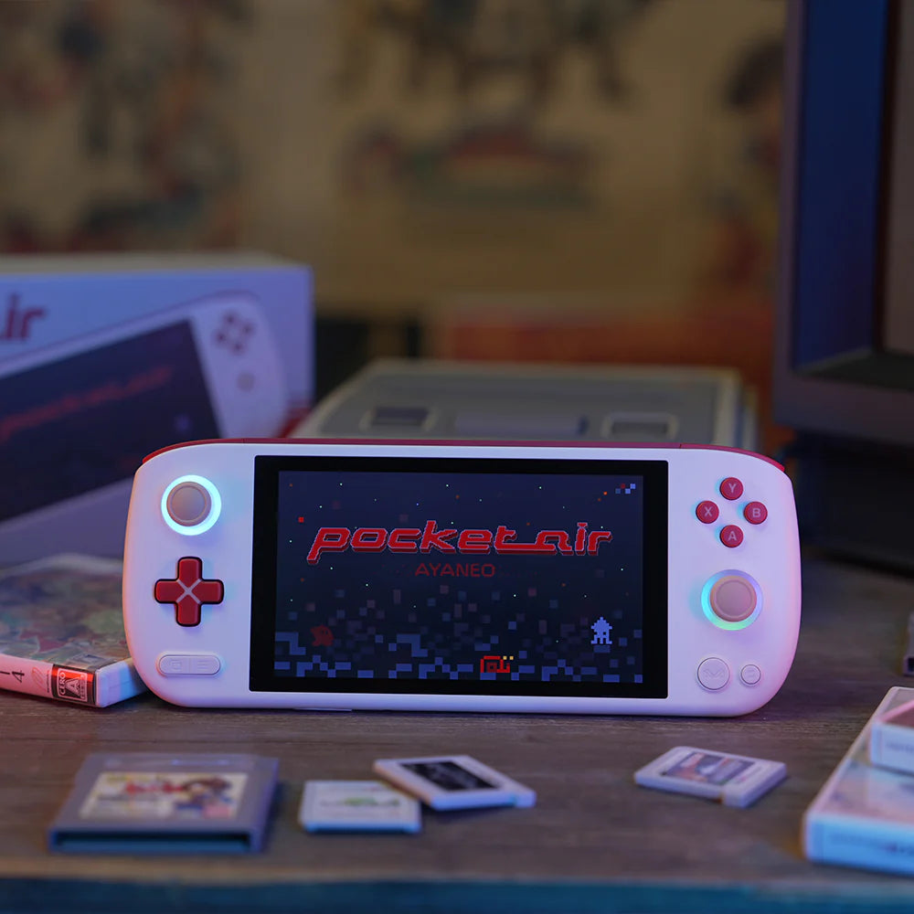 Console AYANEO Pocket AIR affichant un jeu sur son écran avec des cartouches à proximité.
