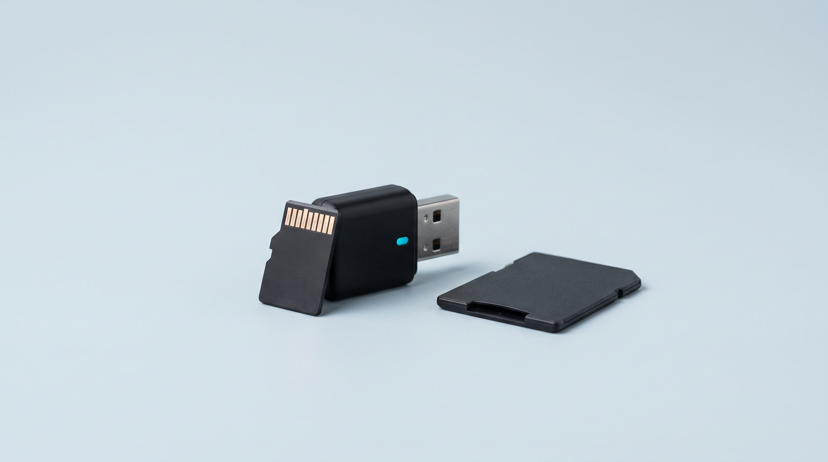 Carte microSD dressée contre un lecteur de cartes USB, avec un adaptateur SD posé à plat