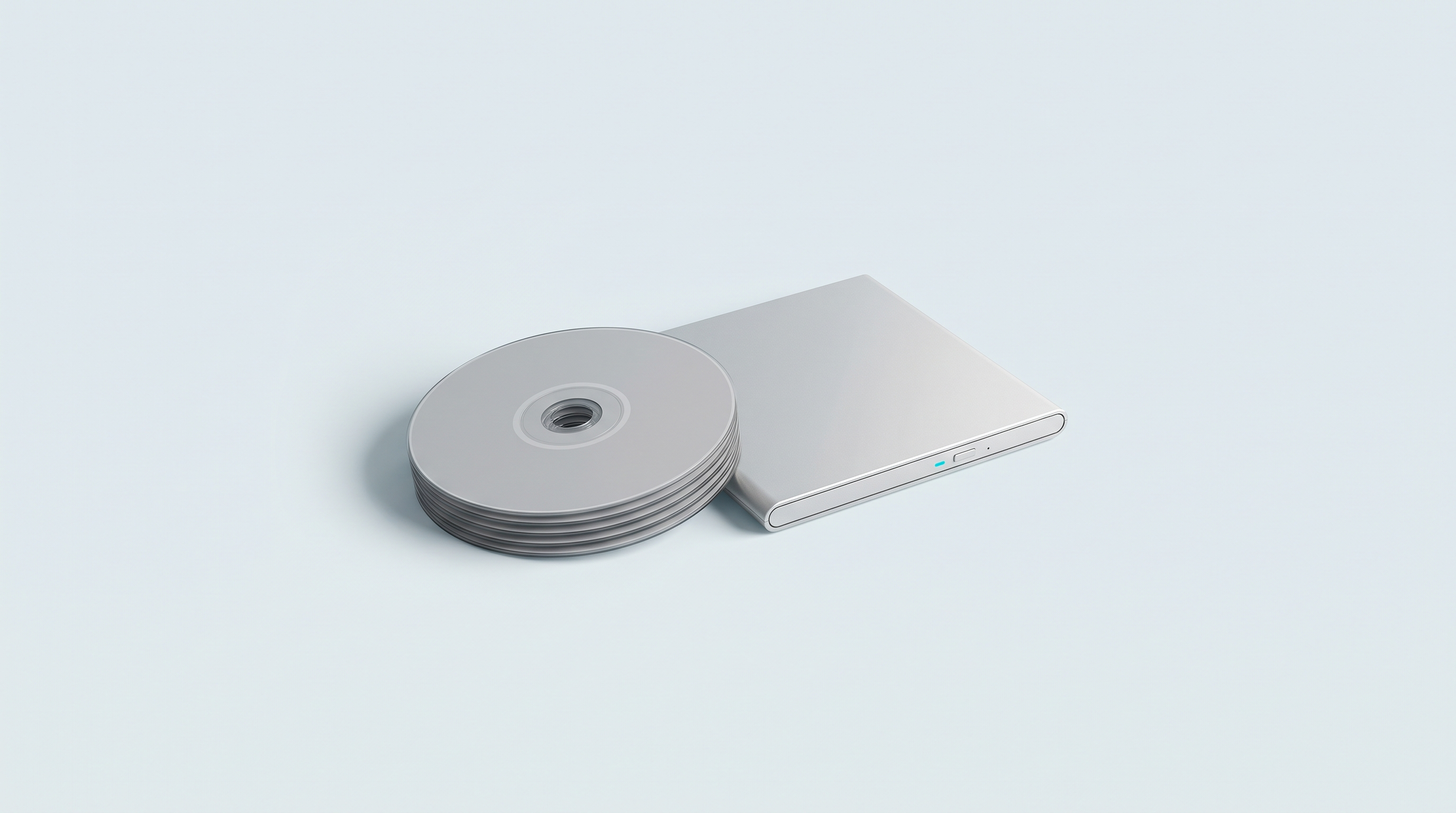 Pile de disques optiques vierges à côté d'un lecteur externe fin et fermé