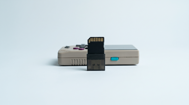 Carte microSD dressée dans un lecteur USB, console portable rétro compacte posée derrière
