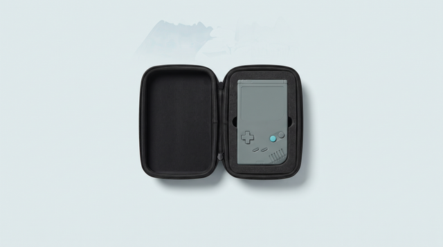 Étui rigide noir ouvert avec une console portable rétro logée dans sa découpe en mousse